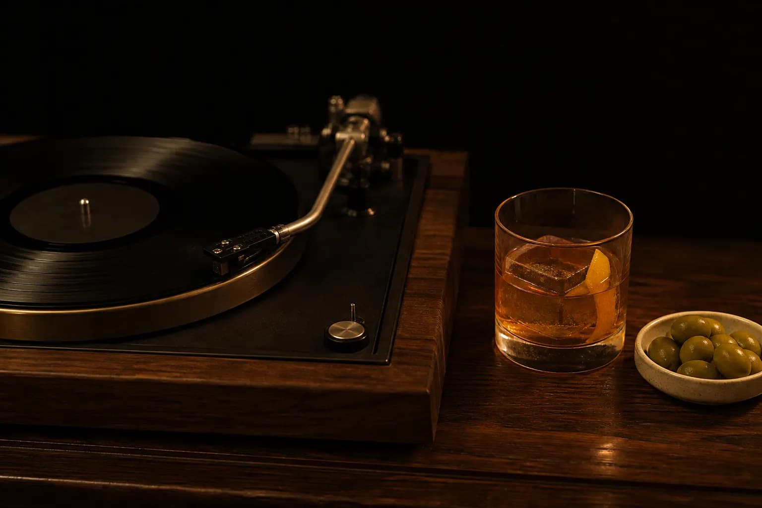 Vintage turntable beside an amber cocktail and olives